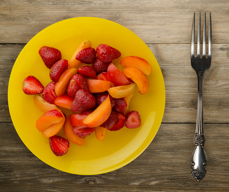healthy food. Strawberries and apricots on a plate. Fruits on a wooden background.の写真素材