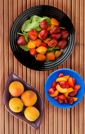 vegetarian food . healthy food. a salad of spinach, apricot, strawberry on a plate on a wooden background.の写真素材