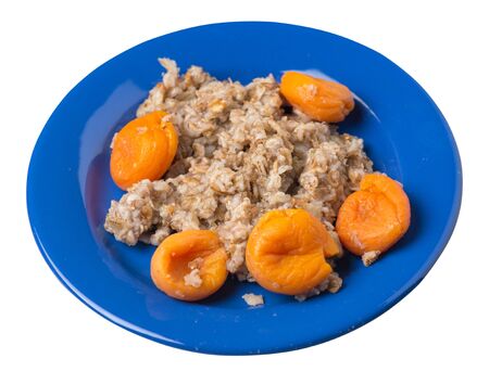 Healthy food .rzhanye flakes with dried apricots on a blue  plate. rainy flakes isolated on white background. top side  view diet breakfastの写真素材