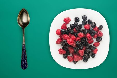 blackberry and raspberry on a white plate. blackberry and raspberries on a turquoise  background top view. Vegetarian food.の写真素材