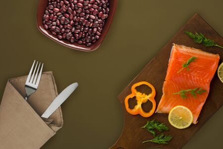 red fish trout fillets on a brown wooden  plate. fish trout on a brown green background. trout with dill, lemon and pepper top viewの写真素材