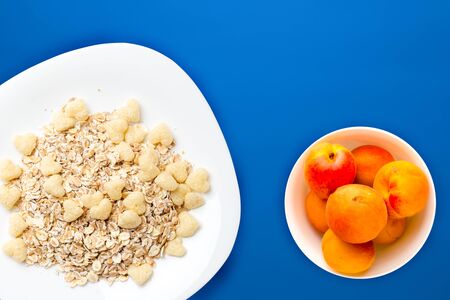 granola on a white plate on blue background.muesli with fruit on a plate top view. healthy eating. Healthy breakfast. Vegetarian foodの写真素材
