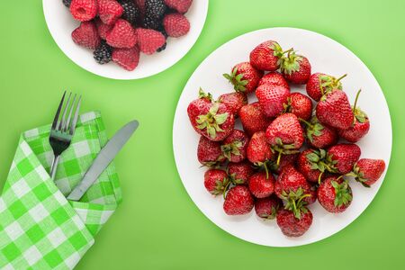 strawberries on a white plate top view. Strawberries on the  lime background. Healthy food. vegan food.の写真素材