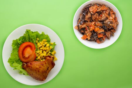 chicken wing with lettuce, corn and tomatoes on a white plate. chicken wing with vegetable salad   on a lime background top viewの写真素材