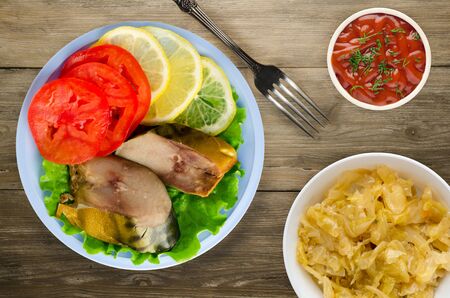 smoked mackerel on a plate. mackerel with lemon and tomato on a wooden backgroundの写真素材