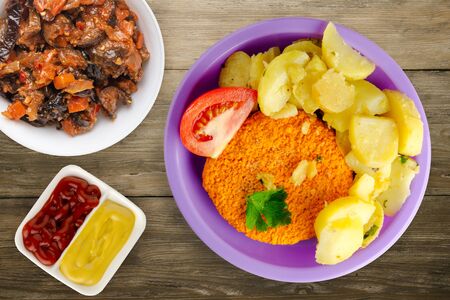 meatball  with potatoes on a wooden background. meatball with a slice of tomato on a purple plateの写真素材