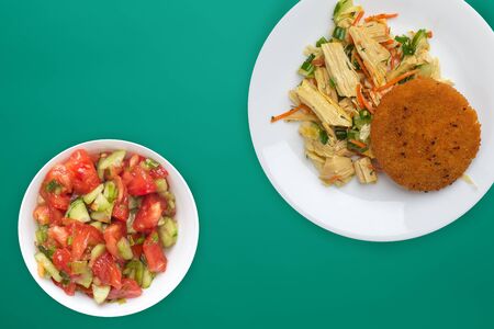 fishcake with soy asparagus and carrots, cucumbers and dill. fish cakes on a white plate on a green background.fish cutlet with vegetables top viewの写真素材