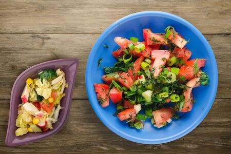 vegetarian food on blue plate with vegetable salad top view . tomatoes, onion, fennel on a plate on brown wooden background. healthy foodの写真素材