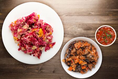 herring under a fur coat on a white plate. Herring under a fur coat on a brown wooden background. herring, beetroot, carrot, mayonnaise and onion salad .の写真素材