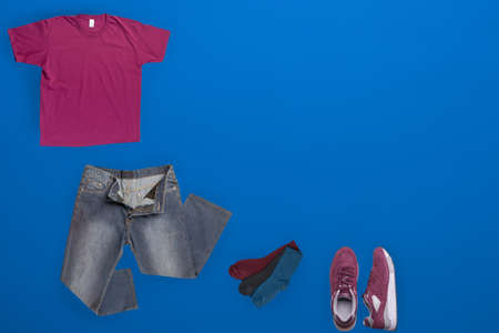 flat lay, men's fashion.bue jeans ,red sneakers,burgundy t-shirt,different colors socks on blue...