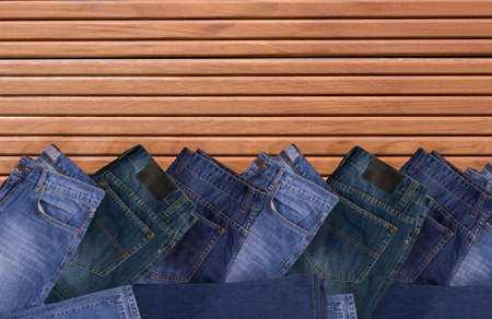 Jeans folded on brown wooden background, Top view with copy work space.