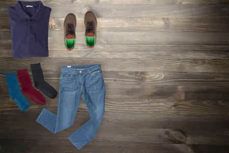 flat lay, men's fashion.blue jeans, brown sneakers, dark blue t-shirt, several color socks on a wooden background. casual clothes top viewの写真素材