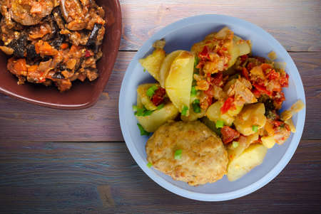 Cutlets with potatoes and stewed tomatoes top view. cutlet on light blue plate with vegetable salad on purple wooden backgroundの写真素材