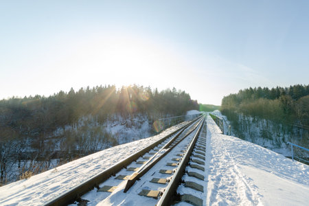 railway passing through the bridge over winter forest. sunny weather in winter. nature in winterの写真素材