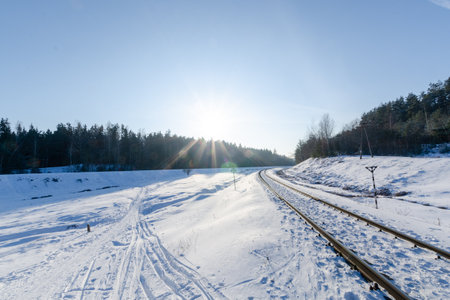 railway passing through the winter forest. sunny weather in winter. nature in winterの写真素材
