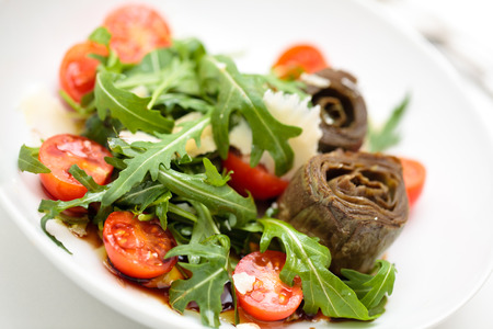 Salad with artichokes, leaves of arugula cherry tomatoes and olive oil.の写真素材