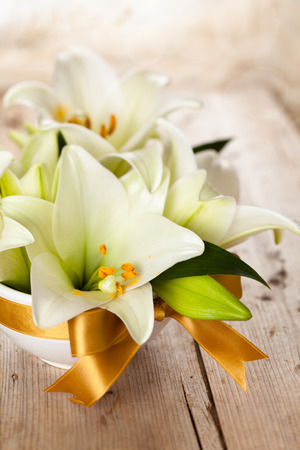 Closeup shot of white lilies on wooden table.の写真素材