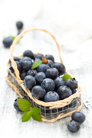 Fresh blueberries in small basket with mint .  On white wooden table.の写真素材