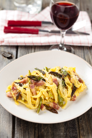 Italian pasta carbonara with asparagus. On wooden rustic table.の写真素材