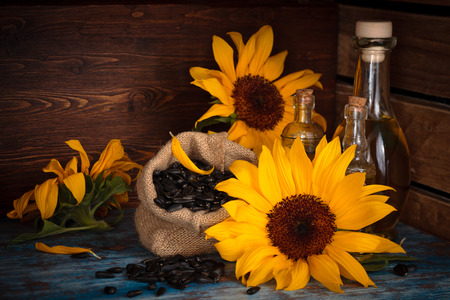 Sunflowers, sunflower oil and sunflower seeds  in rustic background.の写真素材