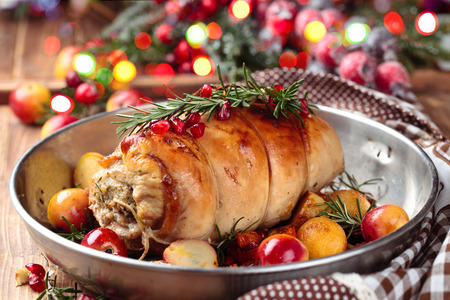 Stuffed turkey breast with baked vegetables and spices against holiday lights background.の写真素材