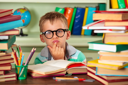 Education and school concept - little schoolboy wearing glasses in the library.の写真素材
