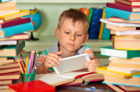 Education and school concept - little schoolboy with tablet  in the library.の写真素材