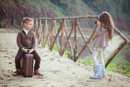 Girl and boy with an old suitcase playing in park.の写真素材