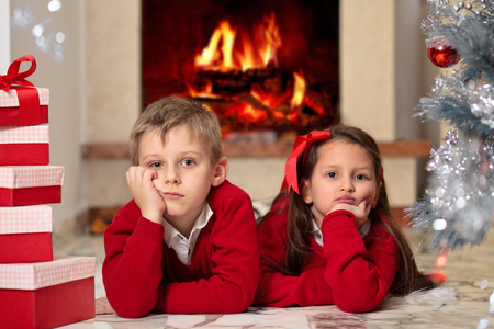 Kids resting on fur near Christmas tree and fireplace.の写真素材