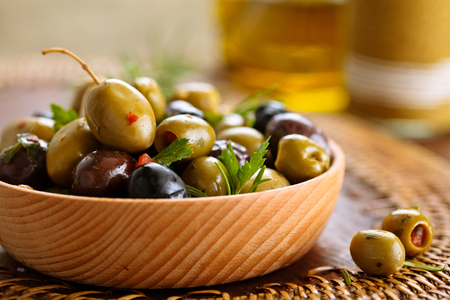 Close-up shot of marinated olives with herbs and spices on rustic table.の写真素材