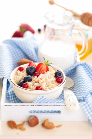 Oatmeal with fresh fruits and honey in small bowls on tray.の写真素材