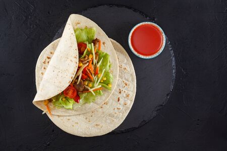 Burritos wraps with chicken and vegetables on black slate. Chicken burrito, mexican foodの写真素材