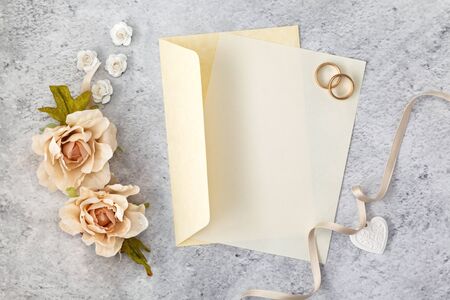 Wedding invitation card  paper laying on table decorated with roses.