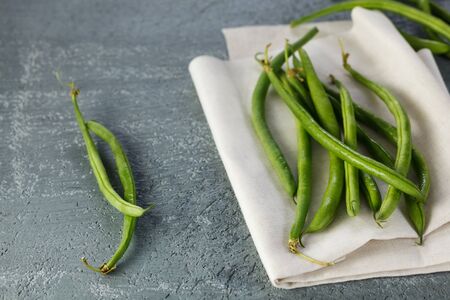 Close up shot of green beans on a grey table.