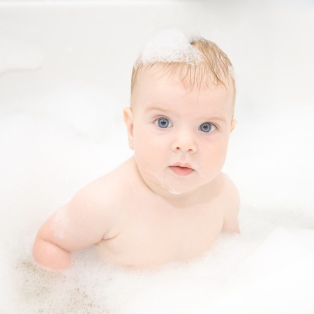 Mother washing baby hair in bath.