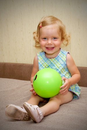 The little blond smiling baby girl with ballの写真素材
