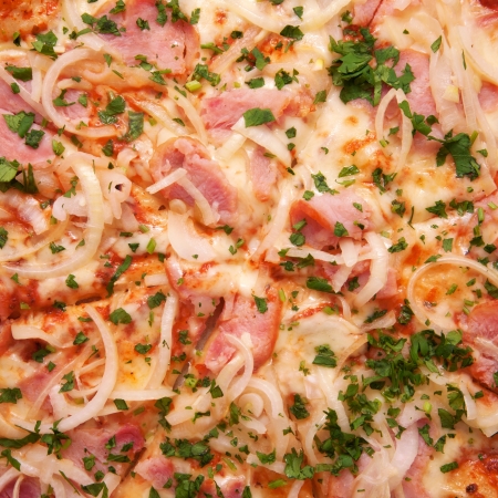 Pizza with ham, onions, cheese and herbs as food background or texture.の写真素材