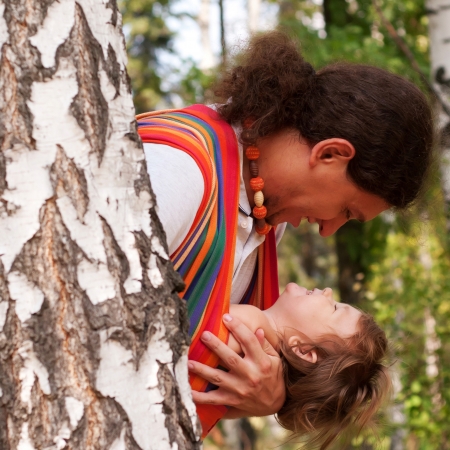 Happy father and kid playing and laughing in forest. Baby sitting in a sling.の写真素材