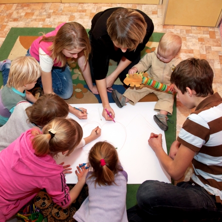 Big happy family - a mother and seven children drawing a heart together at home. Family concept.の写真素材