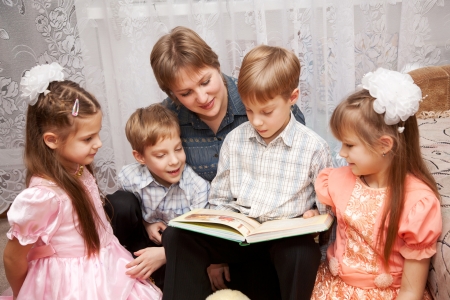 Family concept. Happy mother and four children reading a book. Big family.の写真素材