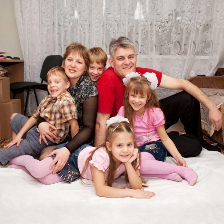 Smiling happy big family at home. Father, mother and four children, two boys and two girls.の写真素材