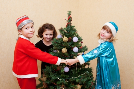 Children in carnival costumes dancing around the Christmas tree.の写真素材