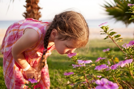 Little girl smelling flowers on the beach. Summer holidays.の写真素材