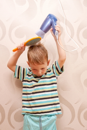 The little boy drying hair with  hair dryer の写真素材