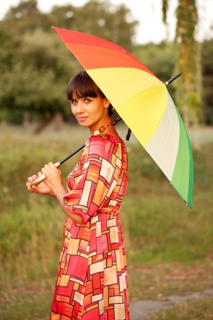Middle-aged woman walking with colorful umbrellaの写真素材