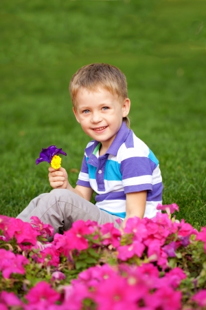Little boy smelling flower close up. Colorful flower meadow.の写真素材
