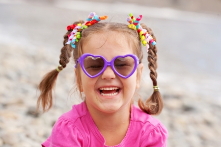 Funny little girl wearing a sunglasses on the beachの写真素材