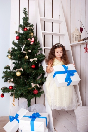 Happy elegant little girl holding gifts near the Christmas tree. Christmas, New Year, holiday conceptの写真素材