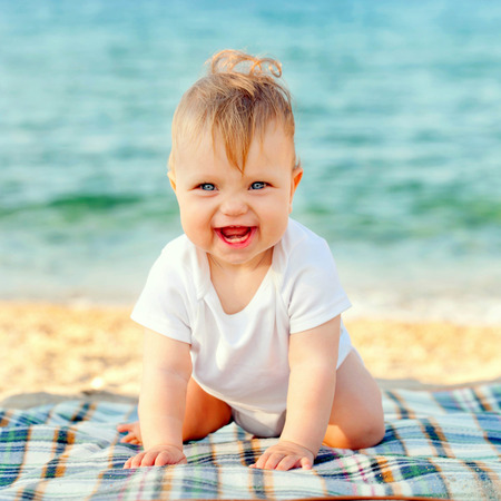 Happy baby on the beach at the seaside. Summer holidays concept
