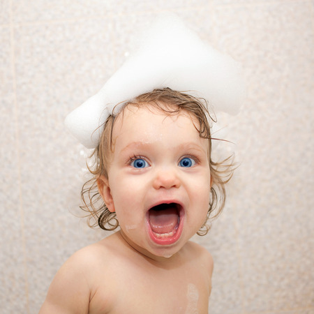Happy bathing baby with foam on his headの写真素材